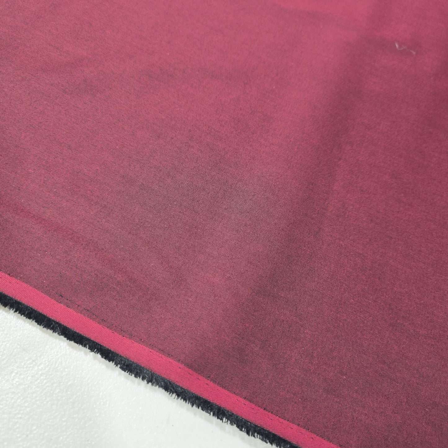 Burgundy 100% cotton chambray fabric draped to showcase its soft lightweight woven texture, 58-inch wide dressmaking fabric sold by the metre.