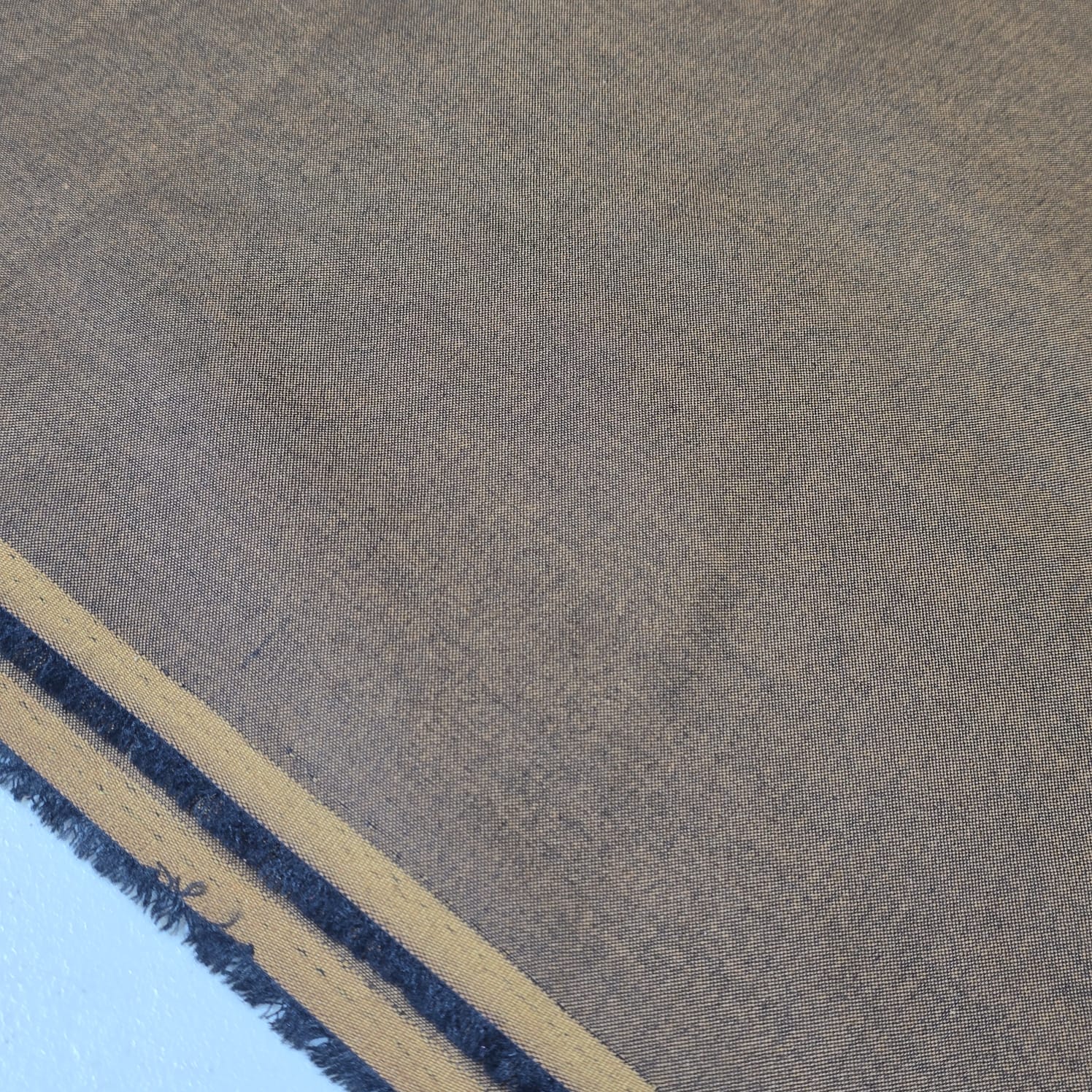Taupe 100% cotton chambray fabric draped to showcase its soft lightweight woven texture, 58-inch wide dressmaking fabric sold by the metre.