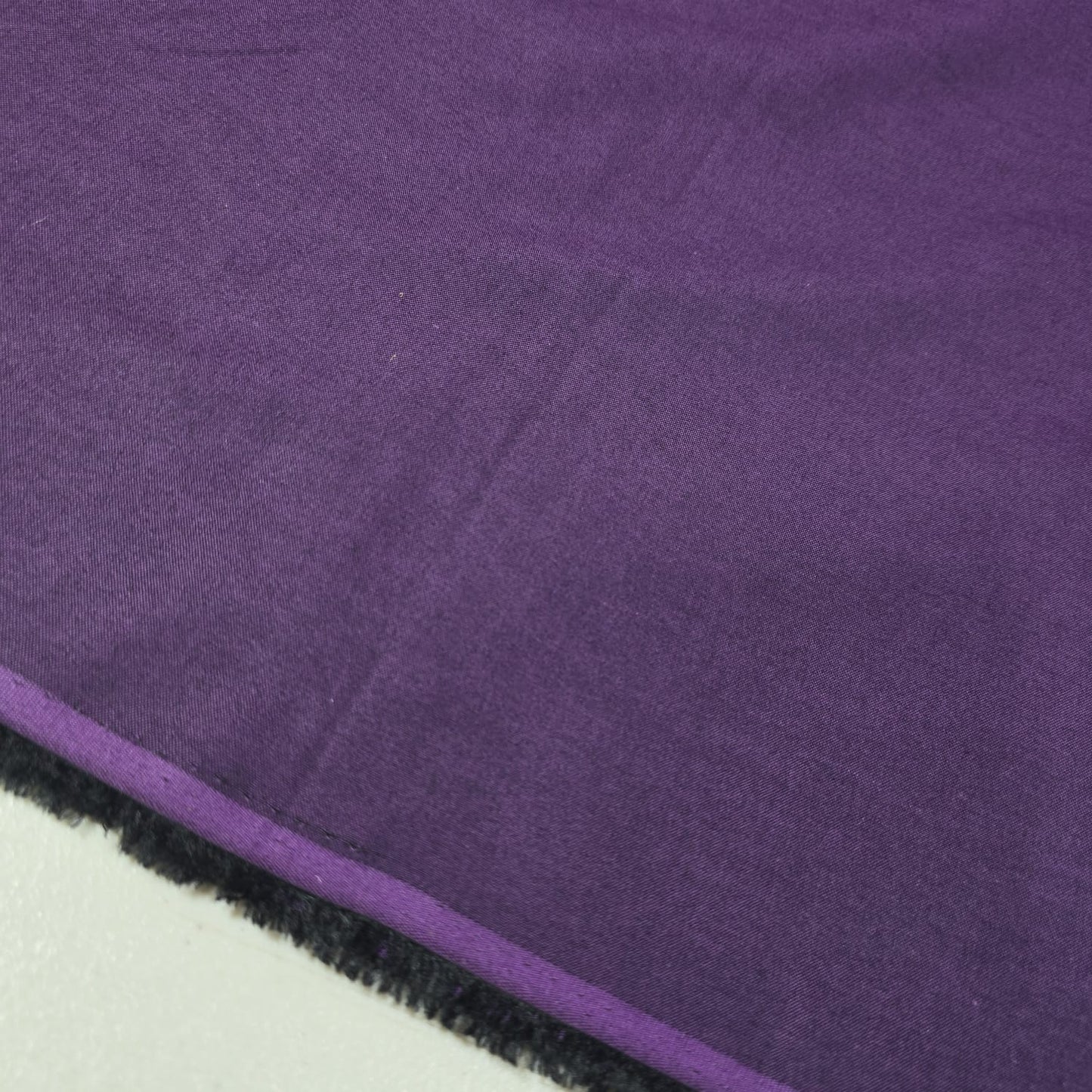 Purple 100% cotton chambray fabric draped to showcase its soft lightweight woven texture, 58-inch wide dressmaking fabric sold by the metre.