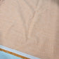 Peach 100% cotton chambray fabric draped to showcase its smooth lightweight woven texture, 58-inch wide dressmaking fabric sold by the metre.