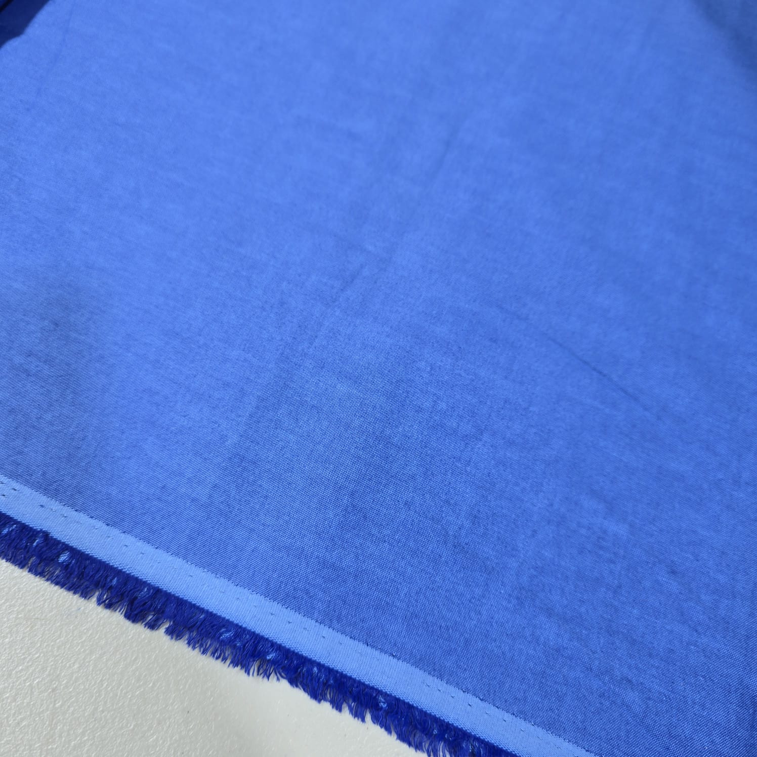 Royal Blue 100% cotton chambray fabric draped to showcase its smooth lightweight woven texture, 58-inch wide dressmaking fabric sold by the metre.